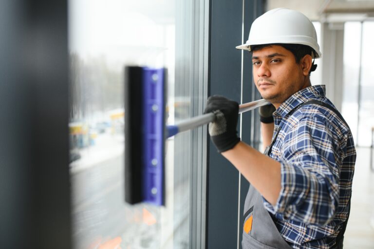 Male professional cleaning service worker cleans the windows and shop windows of a store with special equipment.